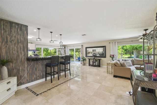 10301 Nina Ct, New Port Richey, FL 34654 - living area featuring plenty of natural light, baseboards, a ceiling fan, light tile patterned floors, and a textured ceiling