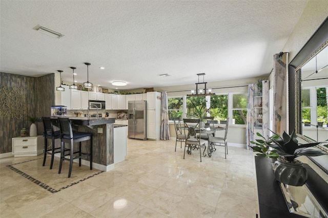 10301 Nina Ct, New Port Richey, FL 34654 - kitchen featuring stainless steel appliances, plenty of natural light, a peninsula, white cabinets, and a textured ceiling