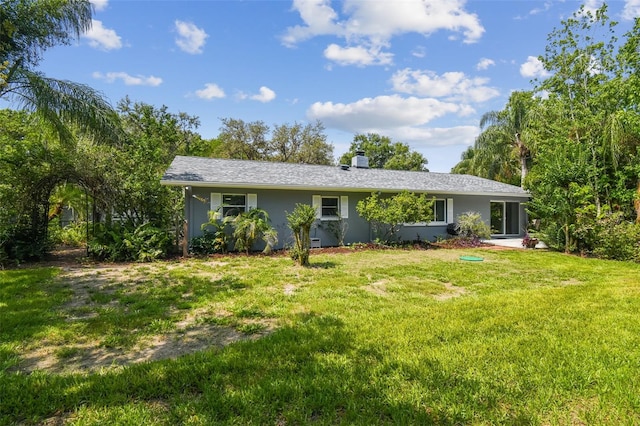 10301 Nina Ct, New Port Richey, FL 34654 - back of property with a lawn, stucco siding, and a chimney