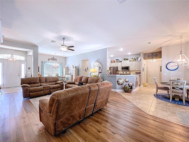 9152 Bunting Rd, Weeki Wachee, FL 34613 - living area featuring a chandelier, light wood-style floors, ceiling fan, and baseboards