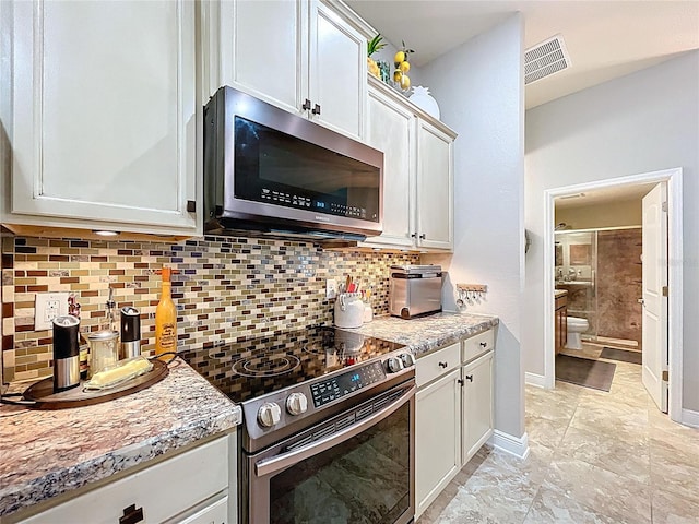 9152 Bunting Rd, Weeki Wachee, FL 34613 - kitchen with stainless steel appliances, decorative backsplash, white cabinets, and baseboards
