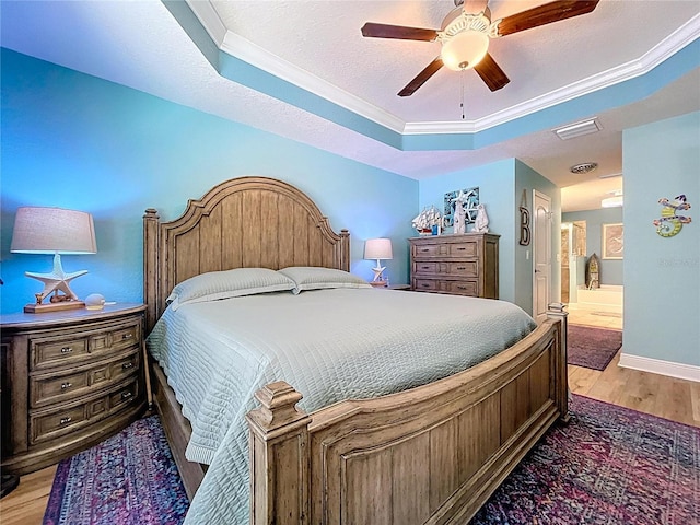 9152 Bunting Rd, Weeki Wachee, FL 34613 - bedroom featuring a tray ceiling, light wood finished floors, crown molding, ensuite bathroom, and a ceiling fan