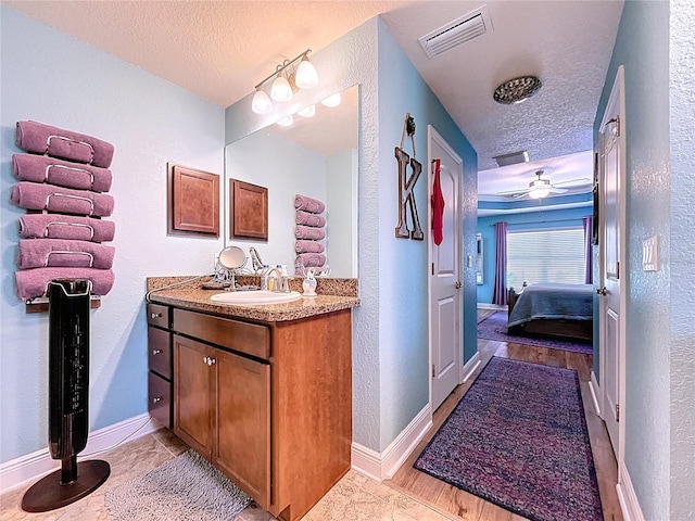 9152 Bunting Rd, Weeki Wachee, FL 34613 - ensuite bathroom with a textured ceiling, a textured wall, vanity, a ceiling fan, and baseboards