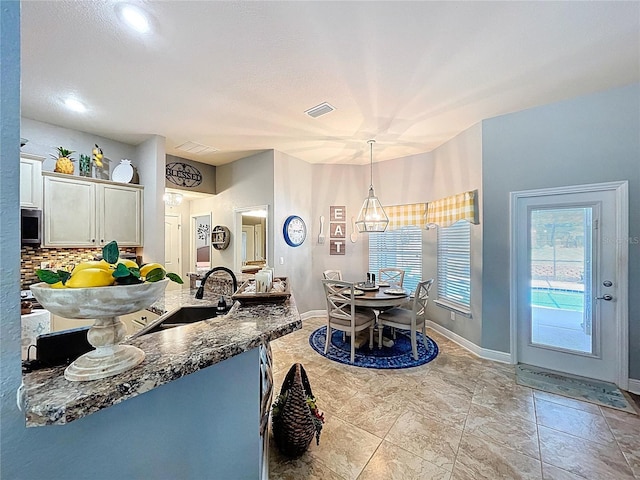 9152 Bunting Rd, Weeki Wachee, FL 34613 - kitchen featuring a sink, decorative backsplash, dark stone countertops, pendant lighting, and baseboards