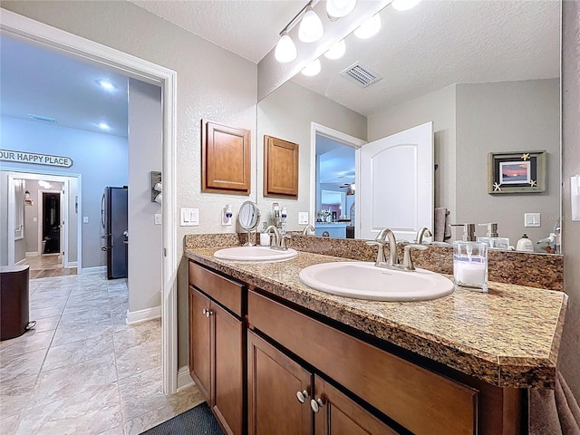 9152 Bunting Rd, Weeki Wachee, FL 34613 - bathroom with double vanity, a textured ceiling, and baseboards