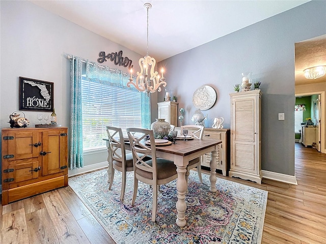 9152 Bunting Rd, Weeki Wachee, FL 34613 - dining room with a chandelier, light wood-style floors, baseboards, and vaulted ceiling