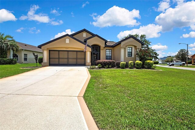 10155 Duffy Cir, Weeki Wachee, FL 34613 - view of front of house with stucco siding, a front yard, an attached garage, and concrete driveway