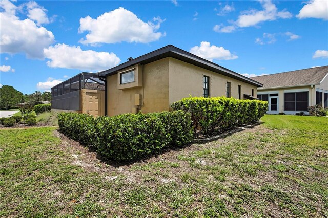 10155 Duffy Cir, Weeki Wachee, FL 34613 - view of side of home featuring stucco siding, a yard, and glass enclosure