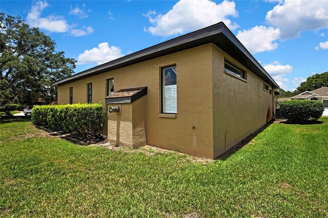 10155 Duffy Cir, Weeki Wachee, FL 34613 - view of side of property featuring stucco siding and a lawn