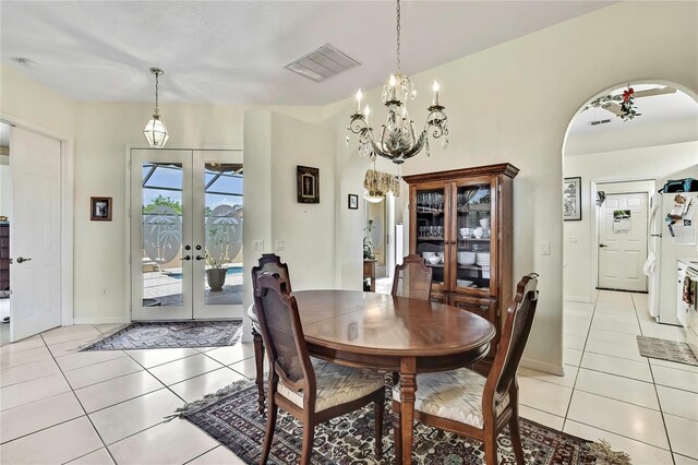 10155 Duffy Cir, Weeki Wachee, FL 34613 - dining room featuring arched walkways, french doors, light tile patterned flooring, and a chandelier