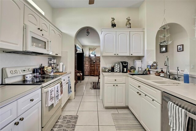 10155 Duffy Cir, Weeki Wachee, FL 34613 - kitchen featuring white appliances, a sink, light tile patterned floors, decorative backsplash, and white cabinets