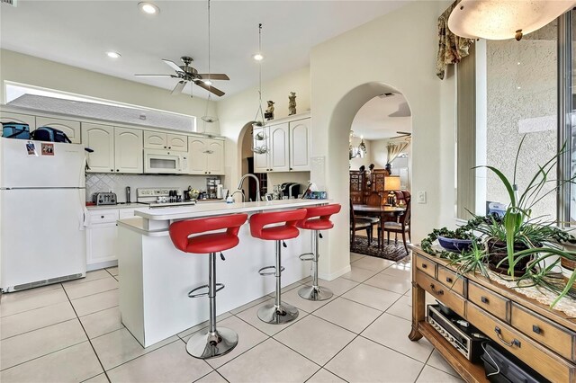 10155 Duffy Cir, Weeki Wachee, FL 34613 - kitchen featuring white appliances, arched walkways, a ceiling fan, a kitchen breakfast bar, and light countertops