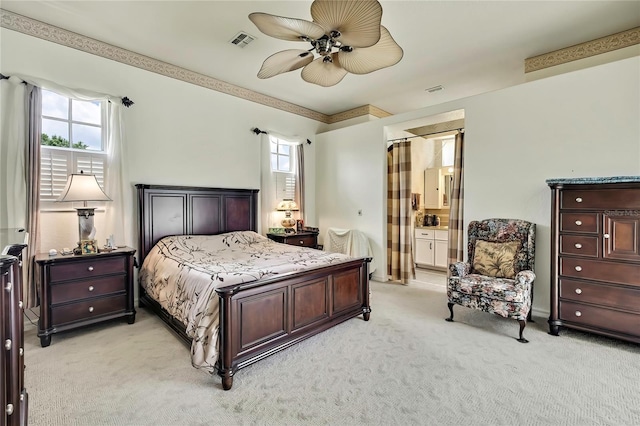 10155 Duffy Cir, Weeki Wachee, FL 34613 - bedroom with multiple windows, light carpet, ensuite bathroom, and ceiling fan