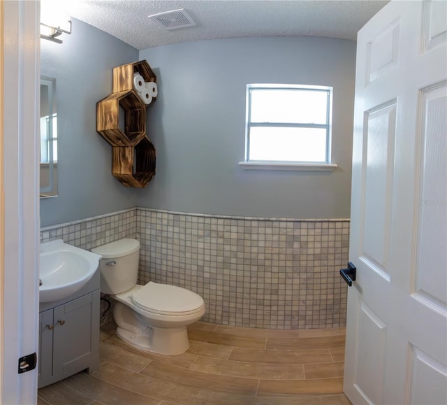 6172 Raleigh St, Spring Hill, FL 34606 - bathroom featuring tile walls, vanity, a wainscoted wall, toilet, and wood finished floors