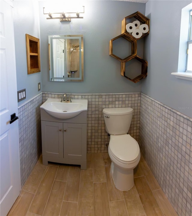6172 Raleigh St, Spring Hill, FL 34606 - bathroom with tile walls, a wainscoted wall, vanity, toilet, and wood finished floors