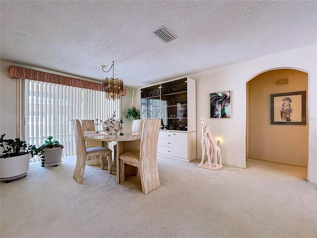 10111 Glen Moor Ln, Port Richey, FL 34668 - carpeted dining room with a chandelier, a textured ceiling, and arched walkways