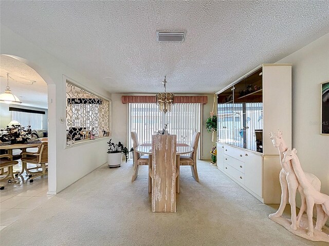 10111 Glen Moor Ln, Port Richey, FL 34668 - dining space with a chandelier, arched walkways, light carpet, and a textured ceiling
