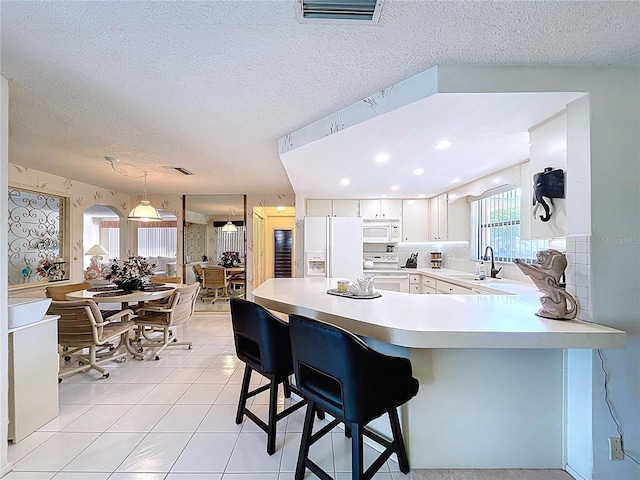 10111 Glen Moor Ln, Port Richey, FL 34668 - kitchen with white appliances, a sink, light countertops, a peninsula, and light tile patterned flooring