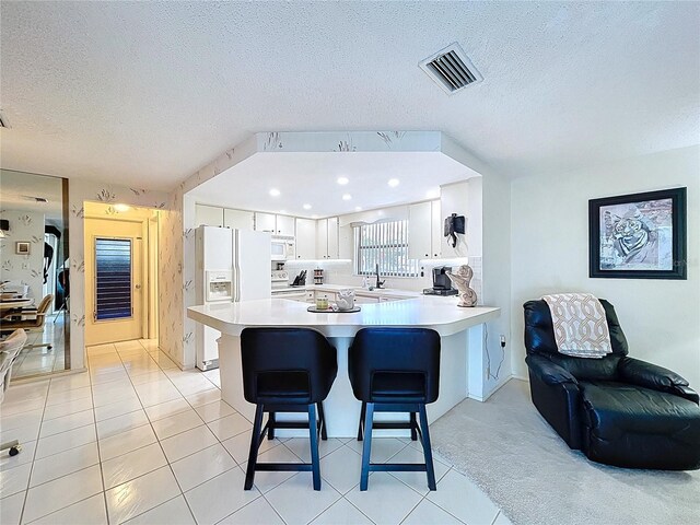 10111 Glen Moor Ln, Port Richey, FL 34668 - kitchen featuring white appliances, a kitchen breakfast bar, light countertops, a textured ceiling, and a peninsula