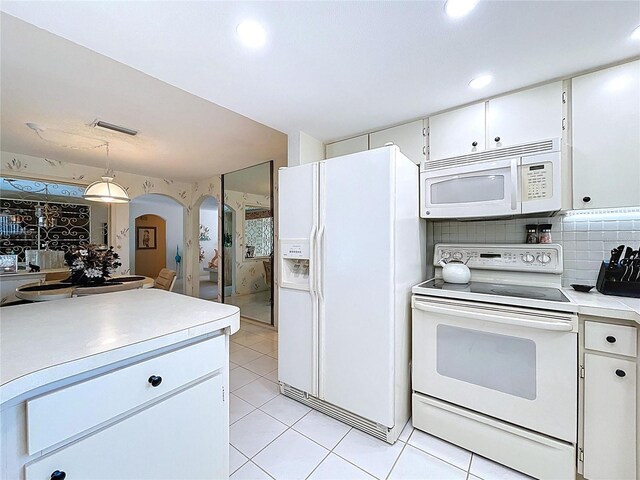 10111 Glen Moor Ln, Port Richey, FL 34668 - kitchen with white appliances, arched walkways, light countertops, white cabinets, and light tile patterned floors