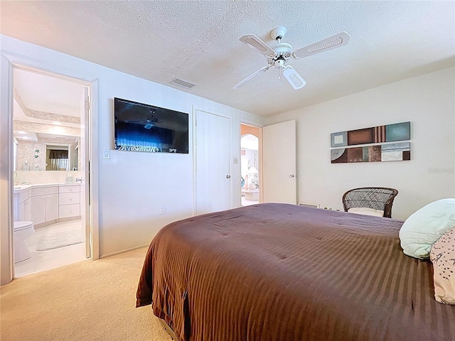 10111 Glen Moor Ln, Port Richey, FL 34668 - bedroom with light colored carpet, ensuite bathroom, ceiling fan, and a textured ceiling