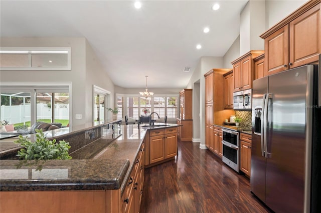 4923 Fort Peck Rd, New Port Richey, FL 34655 - kitchen with stainless steel appliances, lofted ceiling, dark wood-type flooring, a chandelier, and brown cabinetry