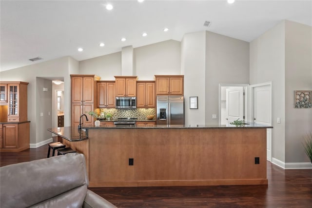 4923 Fort Peck Rd, New Port Richey, FL 34655 - kitchen featuring stainless steel appliances, brown cabinetry, high vaulted ceiling, dark wood-type flooring, and a large island with sink