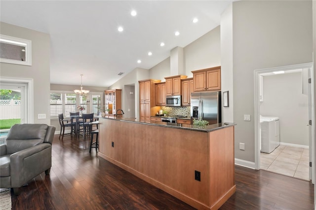 4923 Fort Peck Rd, New Port Richey, FL 34655 - kitchen featuring stainless steel appliances, washer and clothes dryer, a large island, dark wood-style floors, and backsplash