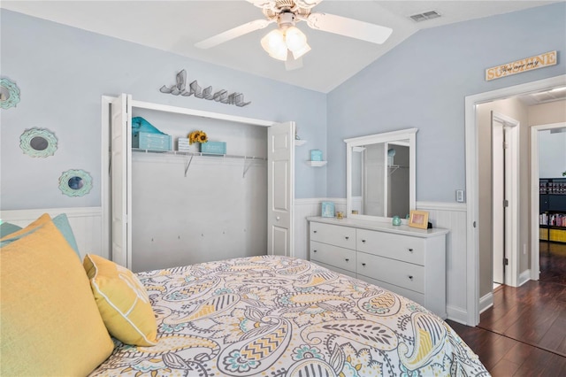 4923 Fort Peck Rd, New Port Richey, FL 34655 - bedroom featuring a closet, a wainscoted wall, vaulted ceiling, dark wood-style floors, and a ceiling fan