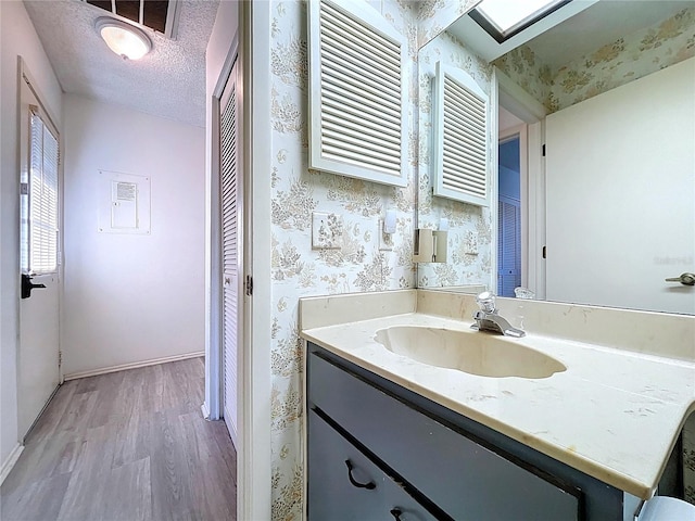 2139 Sea Pines Ct, Spring Hill, FL 34606 - bathroom featuring wood finished floors, vanity, wallpapered walls, baseboards, and a closet