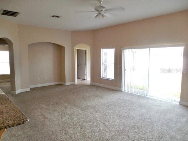 5701 Brackenwood Dr, Spring Hill, FL 34609 - unfurnished living room featuring arched walkways, a ceiling fan, and carpet flooring