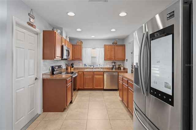 6315 Shane Ln, New Port Richey, FL 34653 - kitchen with appliances with stainless steel finishes, a sink, brown cabinetry, light stone counters, and light tile patterned floors