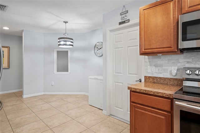 6315 Shane Ln, New Port Richey, FL 34653 - kitchen with appliances with stainless steel finishes, light tile patterned flooring, tasteful backsplash, brown cabinetry, and baseboards