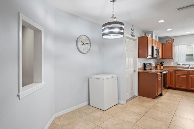 6315 Shane Ln, New Port Richey, FL 34653 - kitchen featuring appliances with stainless steel finishes, a sink, brown cabinets, baseboards, and hanging light fixtures
