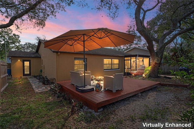 6315 Shane Ln, New Port Richey, FL 34653 - back of property at dusk with stucco siding, a deck, a sunroom, and outdoor dining area