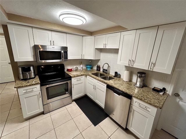7861 Raintree Dr, New Port Richey, FL 34653 - kitchen with stainless steel appliances, a sink, white cabinetry, and a textured ceiling