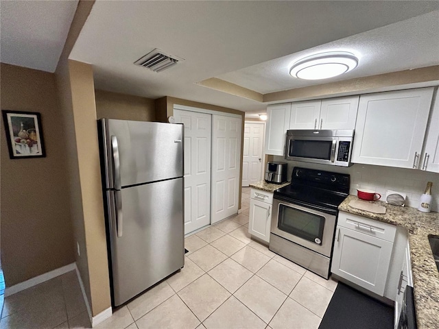 7861 Raintree Dr, New Port Richey, FL 34653 - kitchen featuring appliances with stainless steel finishes, light tile patterned floors, and white cabinetry