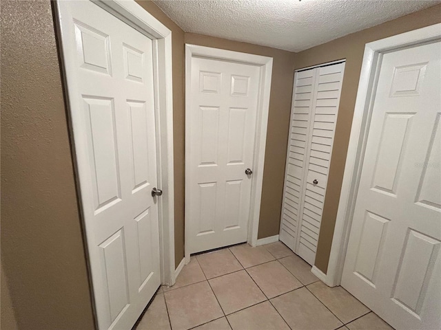7861 Raintree Dr, New Port Richey, FL 34653 - corridor featuring a textured ceiling, light tile patterned flooring, and baseboards