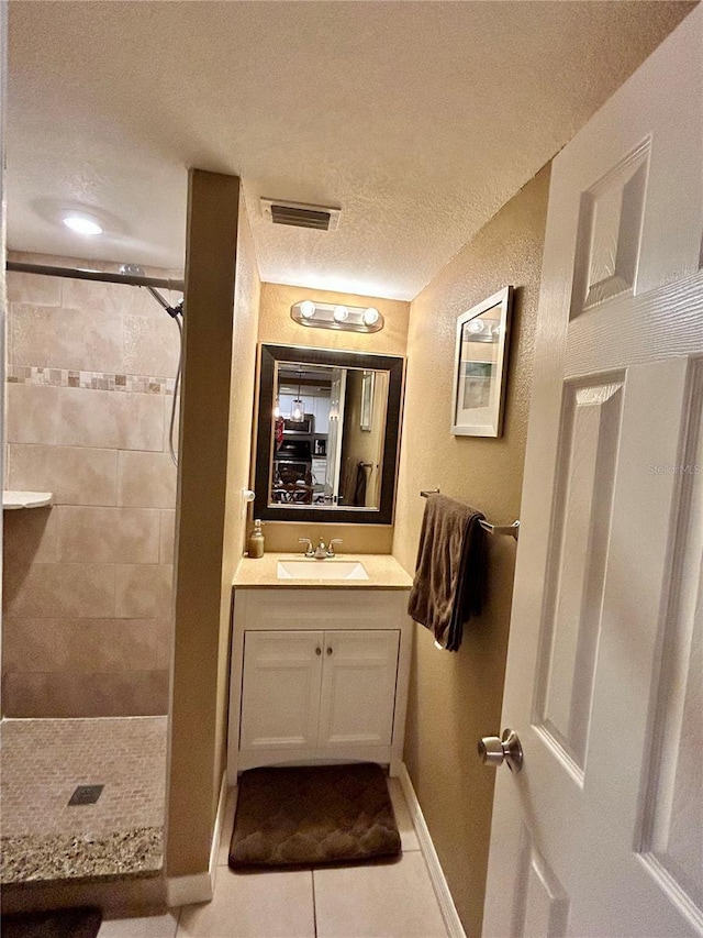 7861 Raintree Dr, New Port Richey, FL 34653 - bathroom featuring a textured ceiling, tiled shower, tile patterned flooring, vanity, and baseboards