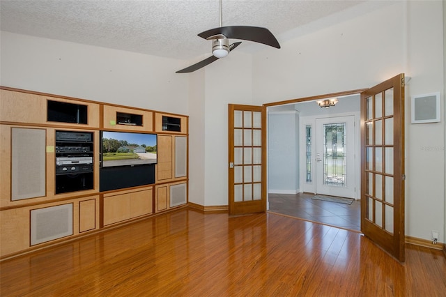 3609 Montclair Dr, New Port Richey, FL 34655 - spare room featuring french doors, wood finished floors, a textured ceiling, a high ceiling, and a ceiling fan