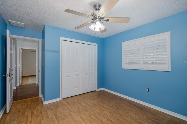 3609 Montclair Dr, New Port Richey, FL 34655 - unfurnished bedroom with light wood-type flooring, a closet, baseboards, a textured ceiling, and a ceiling fan