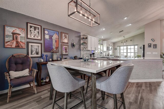 14011 Shoal Dr, Hudson, FL 34667 - dining area with a textured ceiling, wood finished floors, vaulted ceiling, a chandelier, and recessed lighting