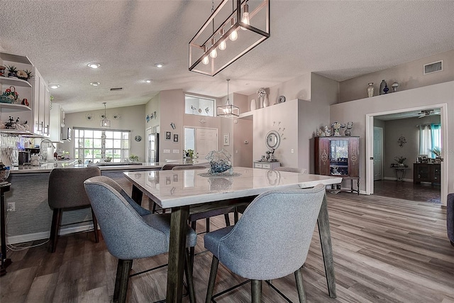 14011 Shoal Dr, Hudson, FL 34667 - dining space featuring a textured ceiling, dark wood-style flooring, a chandelier, and lofted ceiling