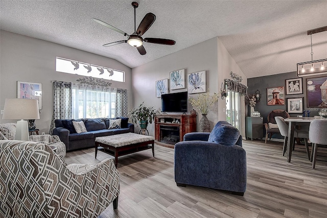 14011 Shoal Dr, Hudson, FL 34667 - living area featuring lofted ceiling, ceiling fan, a textured ceiling, light wood-style floors, and a fireplace