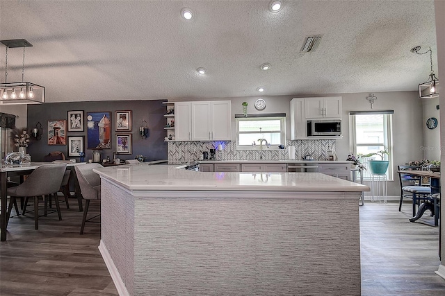 14011 Shoal Dr, Hudson, FL 34667 - kitchen featuring appliances with stainless steel finishes, plenty of natural light, light countertops, wood finished floors, and a textured ceiling