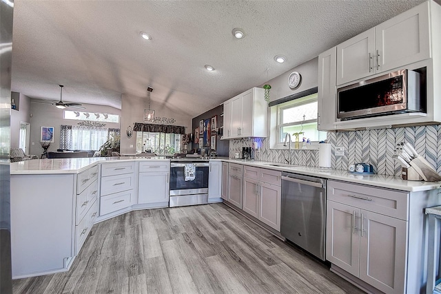 14011 Shoal Dr, Hudson, FL 34667 - kitchen featuring appliances with stainless steel finishes, a textured ceiling, a peninsula, a sink, and light countertops