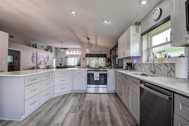 14011 Shoal Dr, Hudson, FL 34667 - kitchen with stainless steel appliances, a sink, a peninsula, a textured ceiling, and light countertops