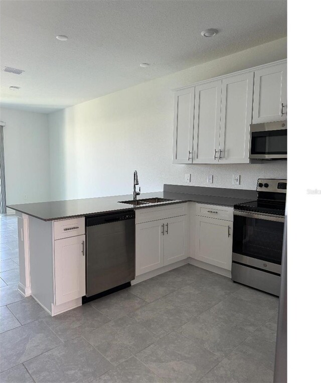 7433 Stone Creek Trl, Kissimmee, FL 34747 - kitchen featuring stainless steel appliances, a sink, a peninsula, and white cabinets