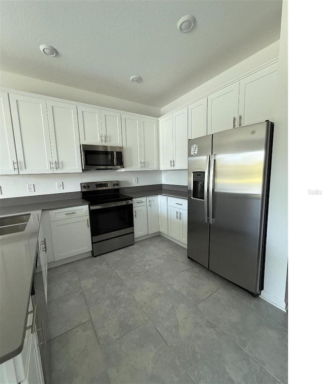 7433 Stone Creek Trl, Kissimmee, FL 34747 - kitchen featuring appliances with stainless steel finishes, white cabinets, dark countertops, and a sink