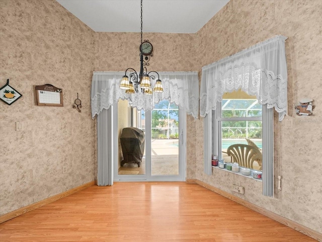 10442 Ventura Dr, Spring Hill, FL 34608 - unfurnished dining area featuring a chandelier, wood finished floors, baseboards, and wallpapered walls